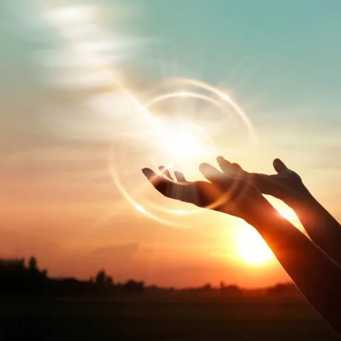 Mains tendues en prière et halo de lumière, Oasis